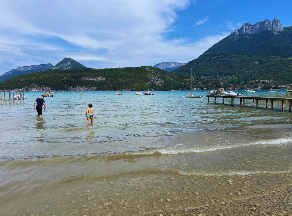 boy wading into the clear water with gorgeous mountain peaks in the back ground
