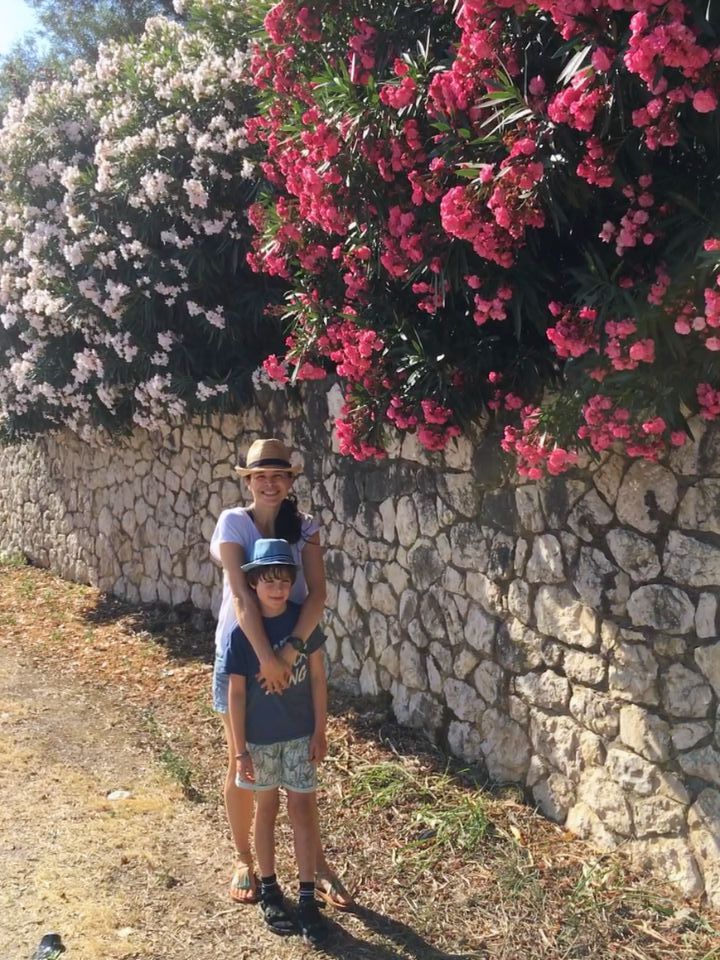 mother and son posing next to flower bushes, pink and white in Lekfada town