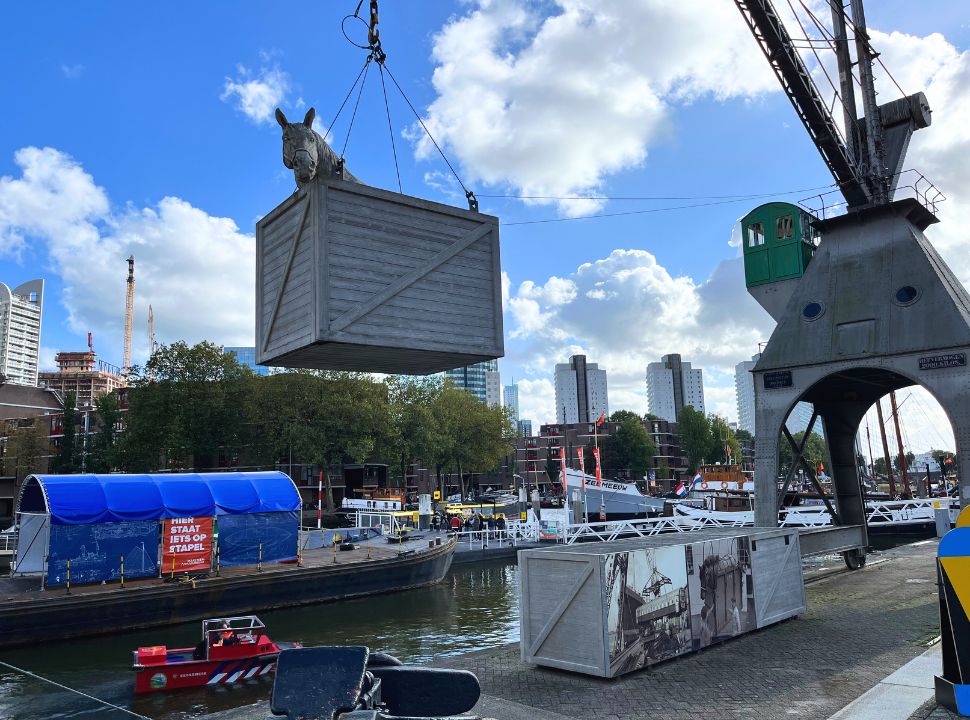 old harbour of Rotterdam where you can see a crane lifting a statue of a horse in a crate