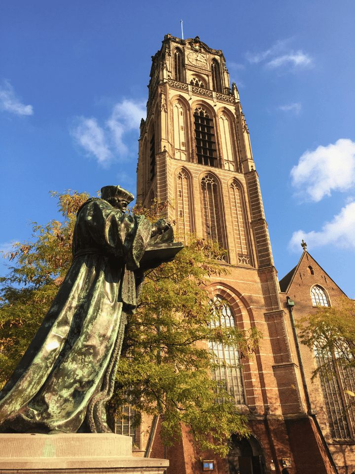 statue with a church in the back in the city center of Rotterdam