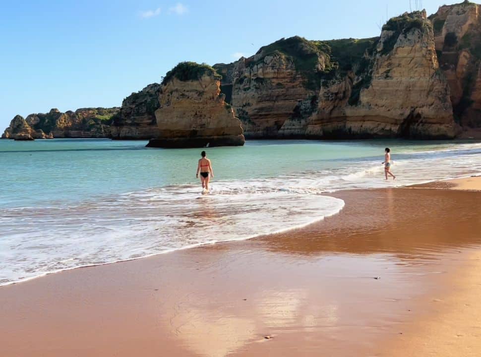 two people walking into the water at Dona Ana beach the algarve portugal