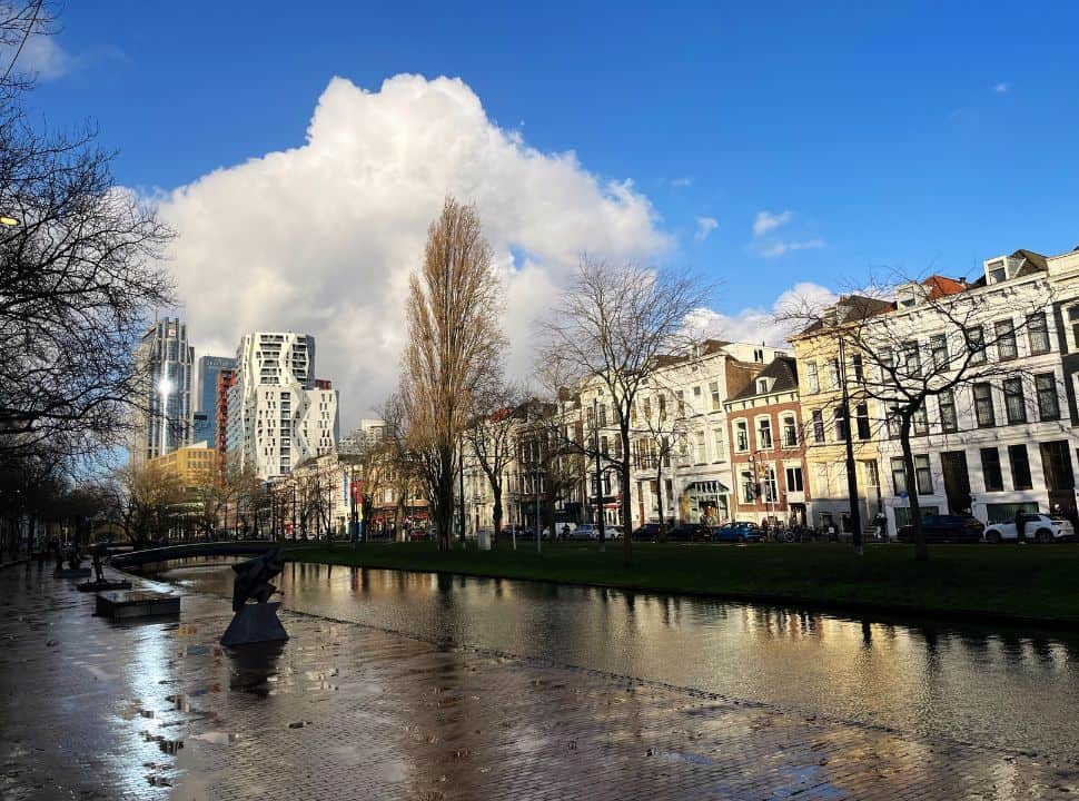 clear skies with one big cloud above a canal in Rotterdam with historic and modern buildings