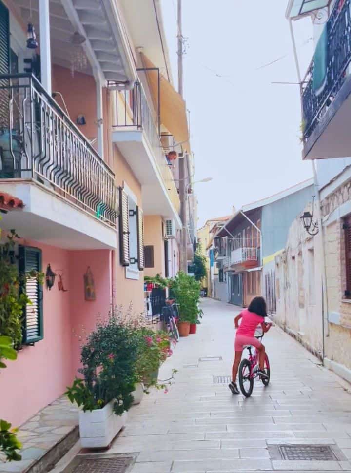 little girl on her bike cycling in the colourful narrow street of old Lefkada town