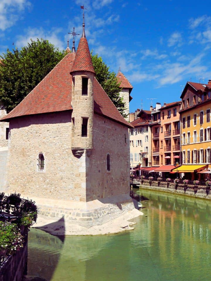 palace in Annecy located right in the middle of a canal, surrounded by clear water and colourful houses