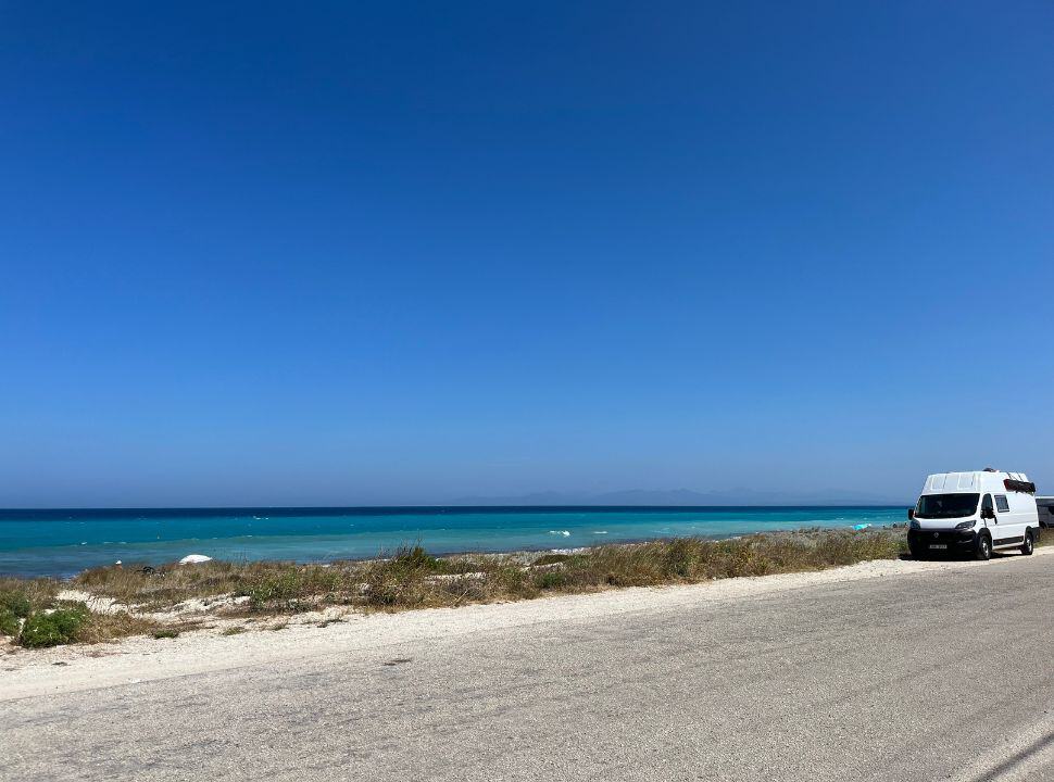 a road running along the beach with a parked white van. 