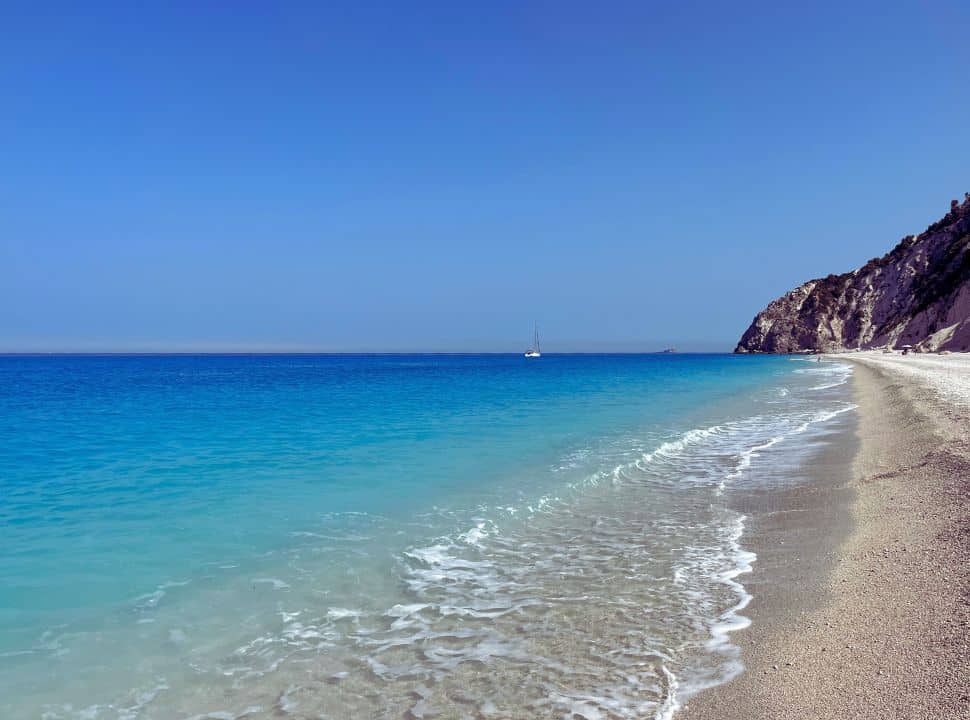 blue water, white cliffs and a sailboat at egremni beach lefkada