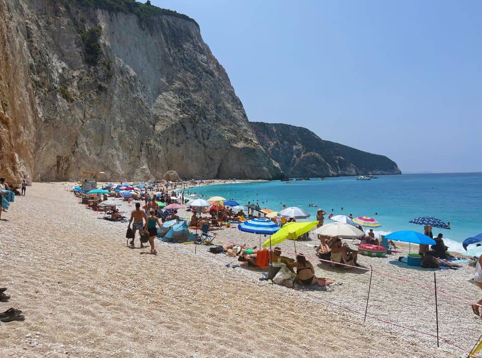 busy beach located at a huge stunning cliff and along a dark blue sea