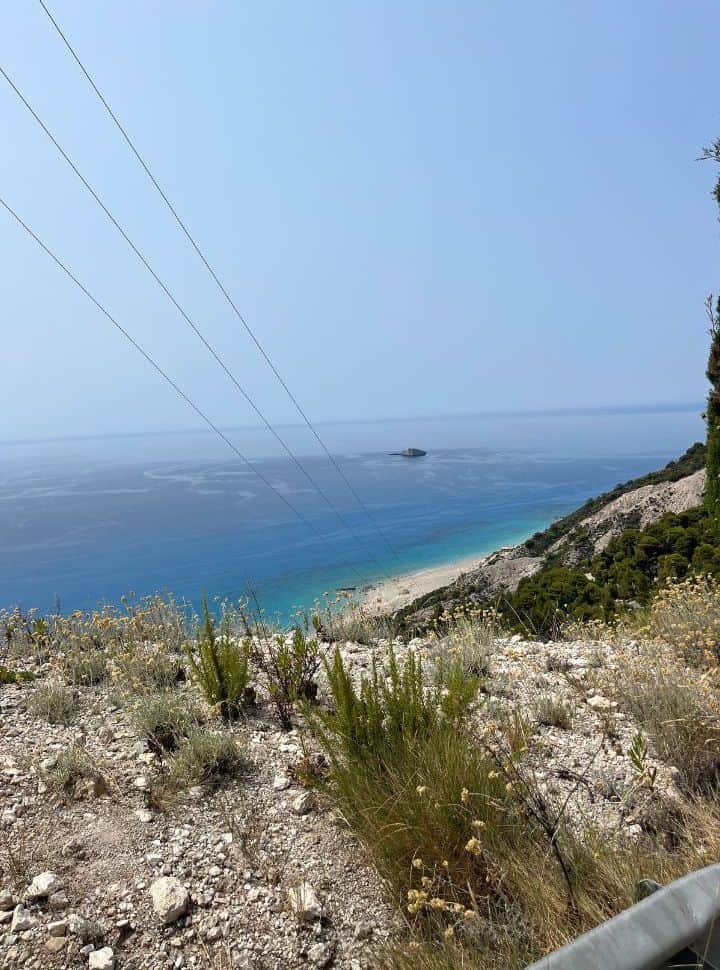 view of a beach with beautiful blue water from a mountain road
