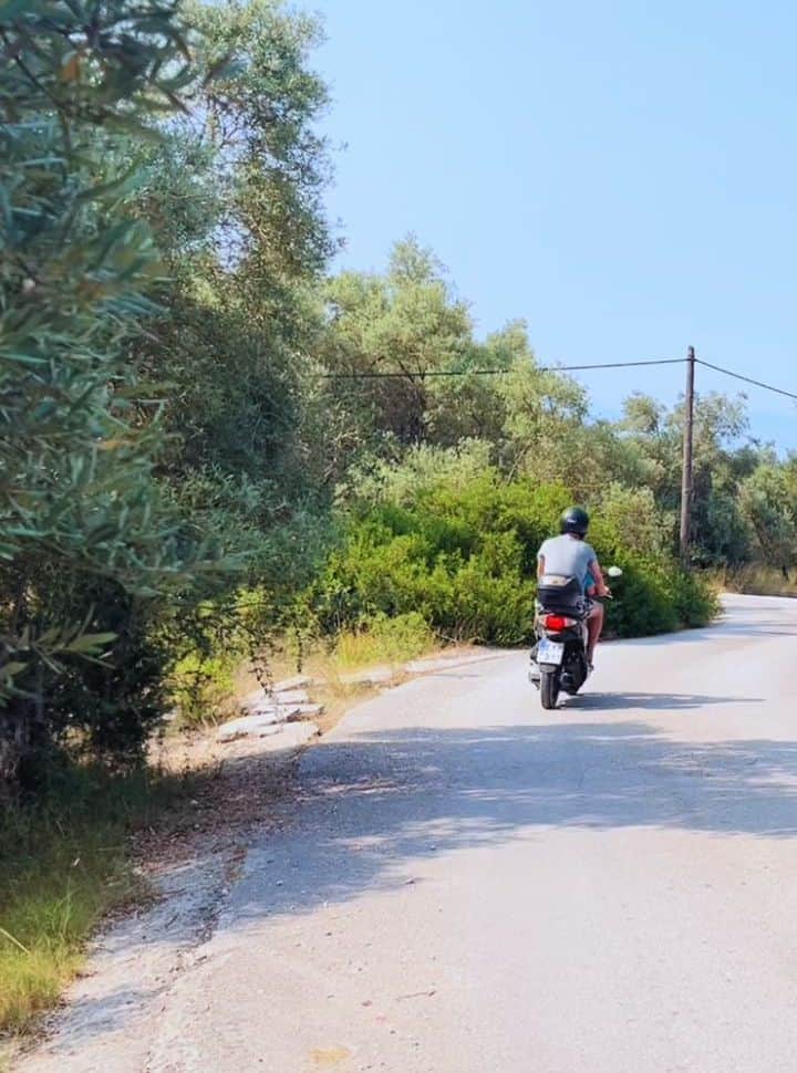 man driving on a scooter through the olive plantations