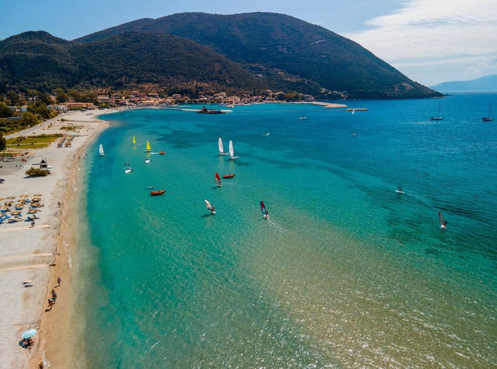windsurfers surfing along vasiliki beach where people are enjoying the long stretched beach