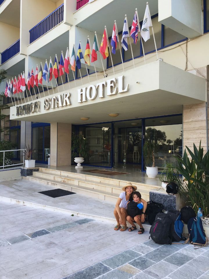 mother and son sitting at the stairs in front of the hotel entrance with all their luggage