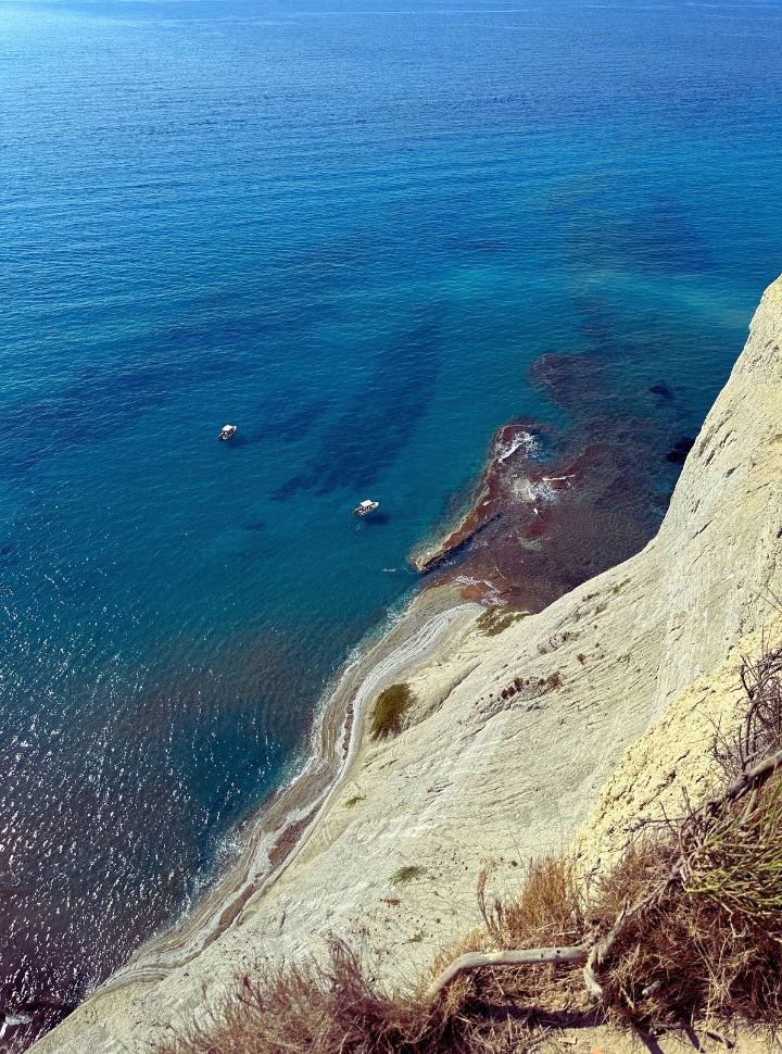 view of the ocean when looking down the high cliff during a hike to cape drastis