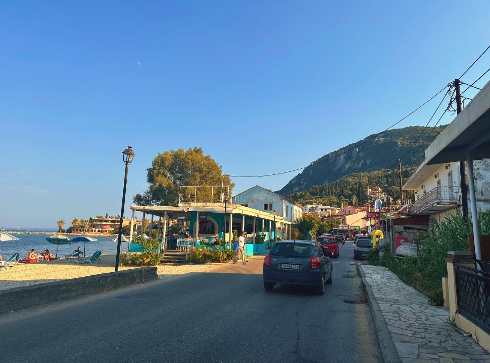 typical village in south corfu set along the main road with beach and restaurant on one side and accomodation and shops on the other