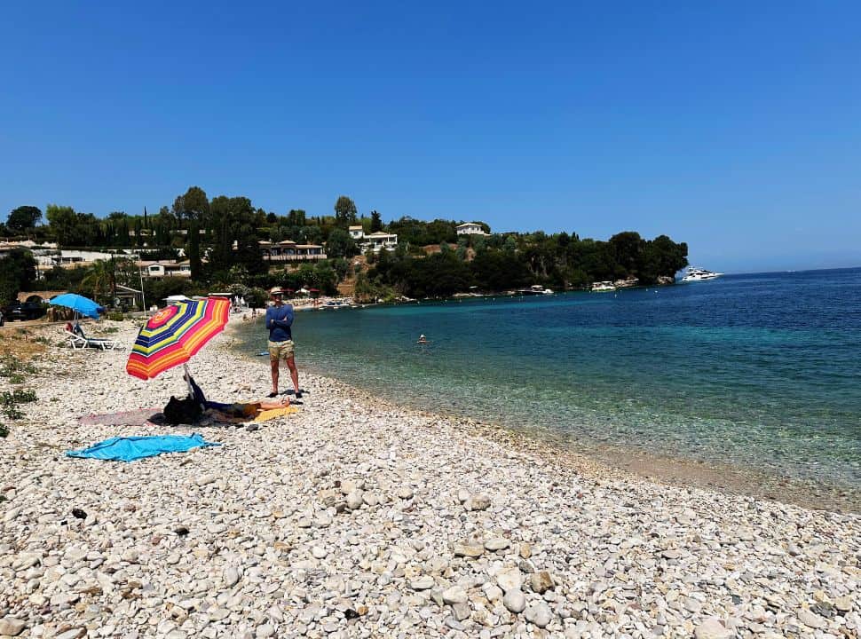 sun umbrella on a quiet pebbled beach with emerald blue water