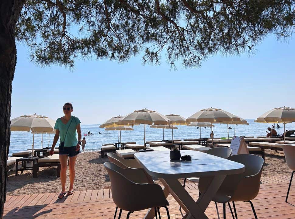 woman walking towards a retaurants set along moraitika beach with sun loungers in south east corfu 