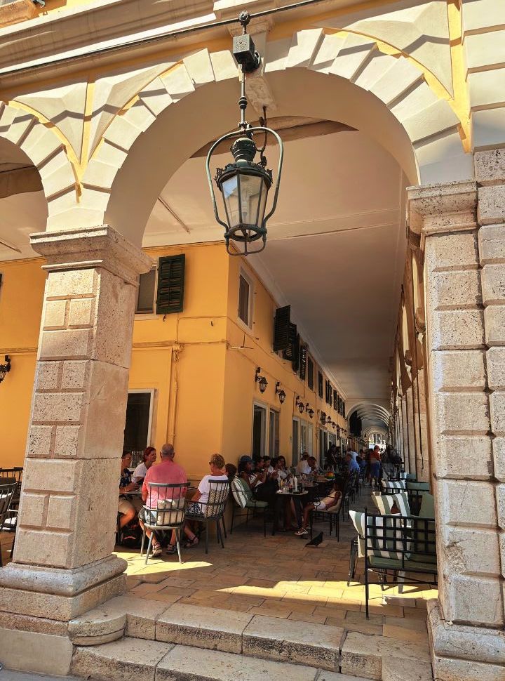 people enjoying food and drinks at the many restaurants in the liston building corfu