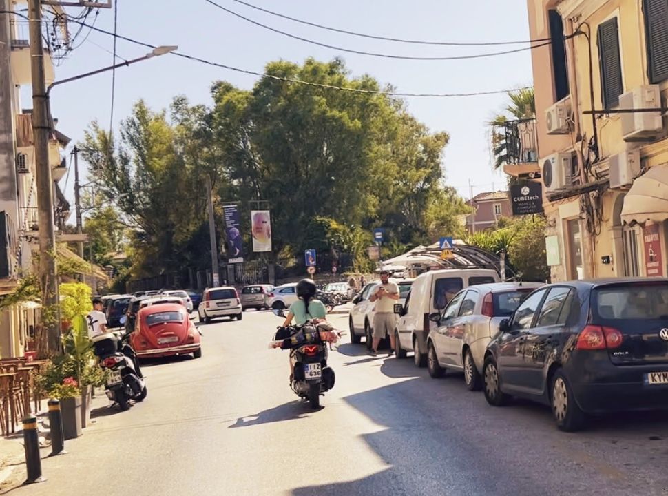 woman on motor scooter driving through the streets of corfu town