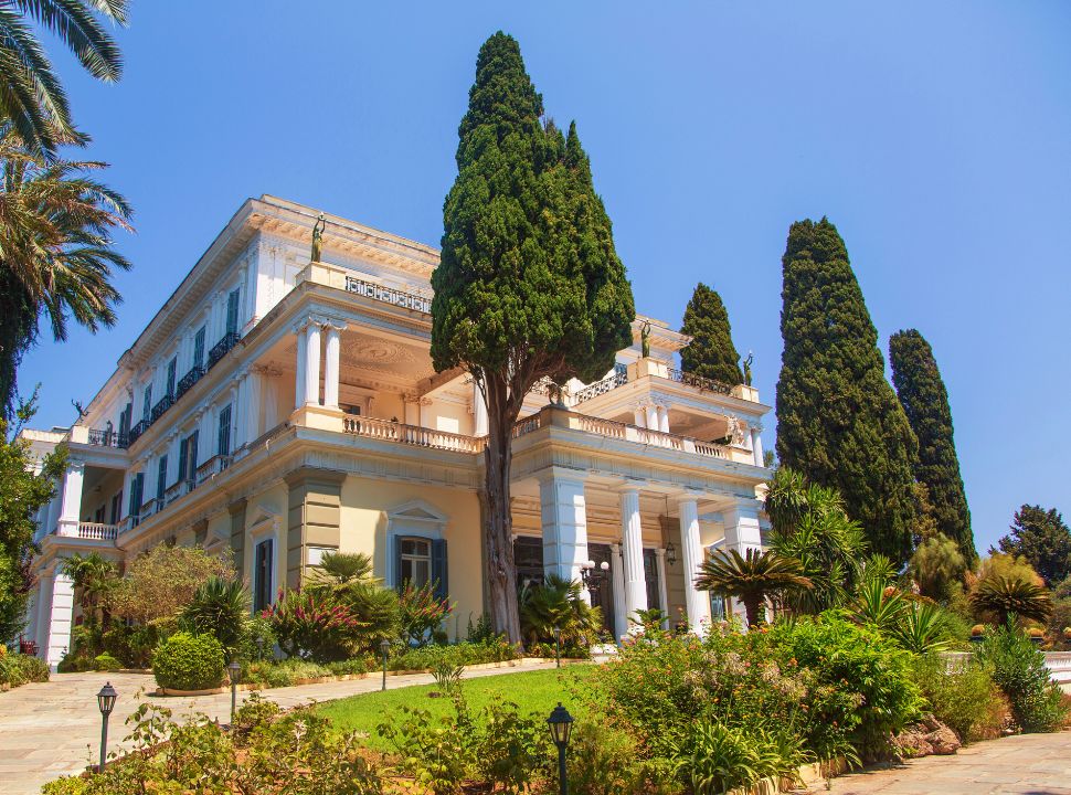 large multiple story mansion with several balconies set within a beautiful garden near corfu town