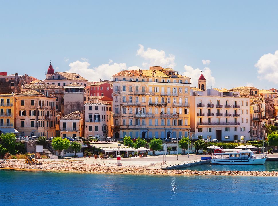 historical buildings of corfu town along the water front, with a boat at the docks