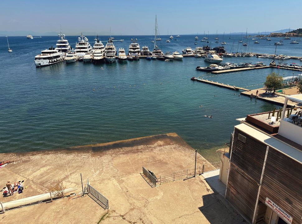 a couple of people lying on the concrete plateau at the edge of the marina where sail boats are docked