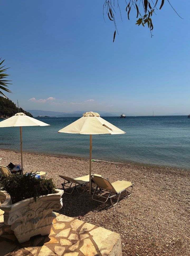 sunloungers and a sun umbrella at the quiet pebbled beach with calm blue water