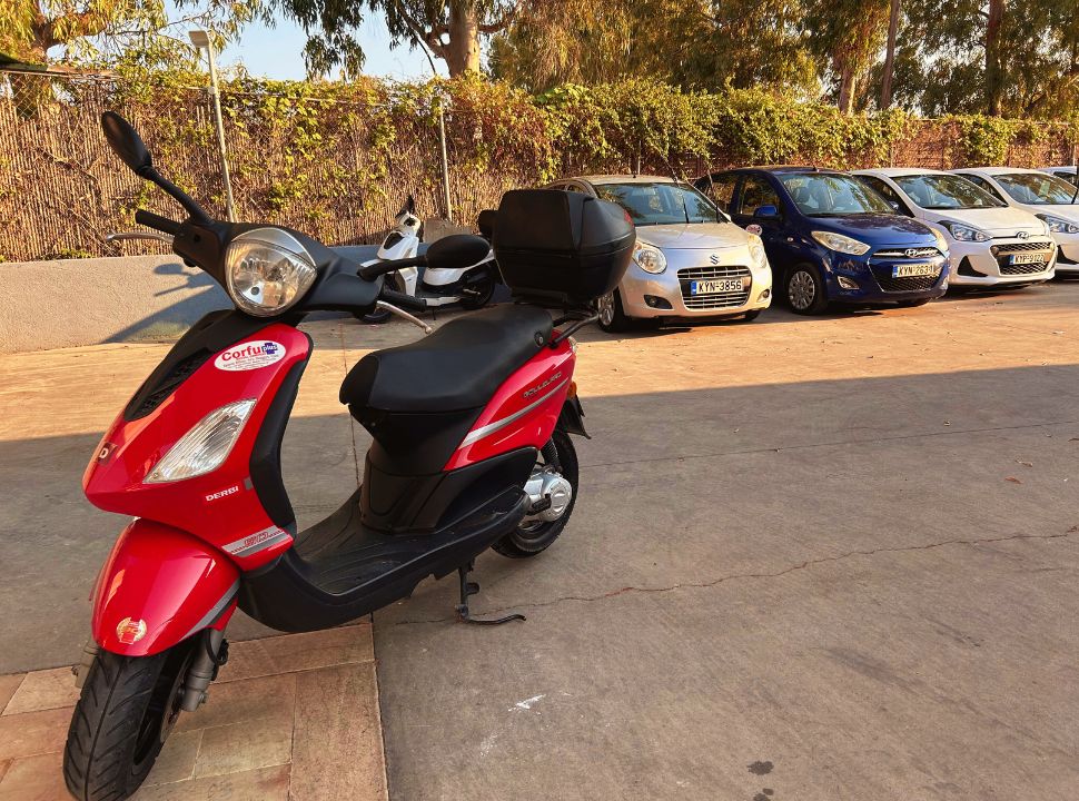 scooter and a row of cars parked at a rental company in corfu