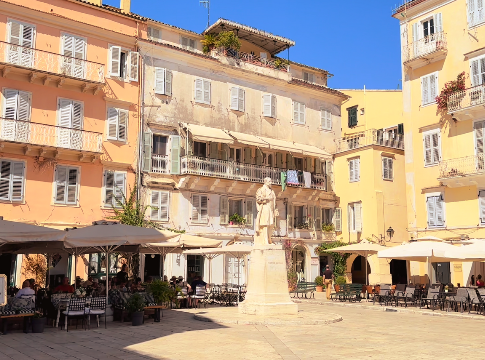 statue located on a square with old colorful buildings with shutters, which are common in corfu old town