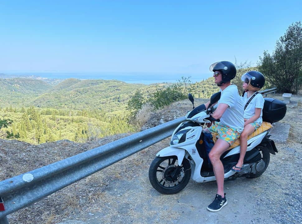 father and son on a motorscooter enjoying the view from the mountains of the green valley