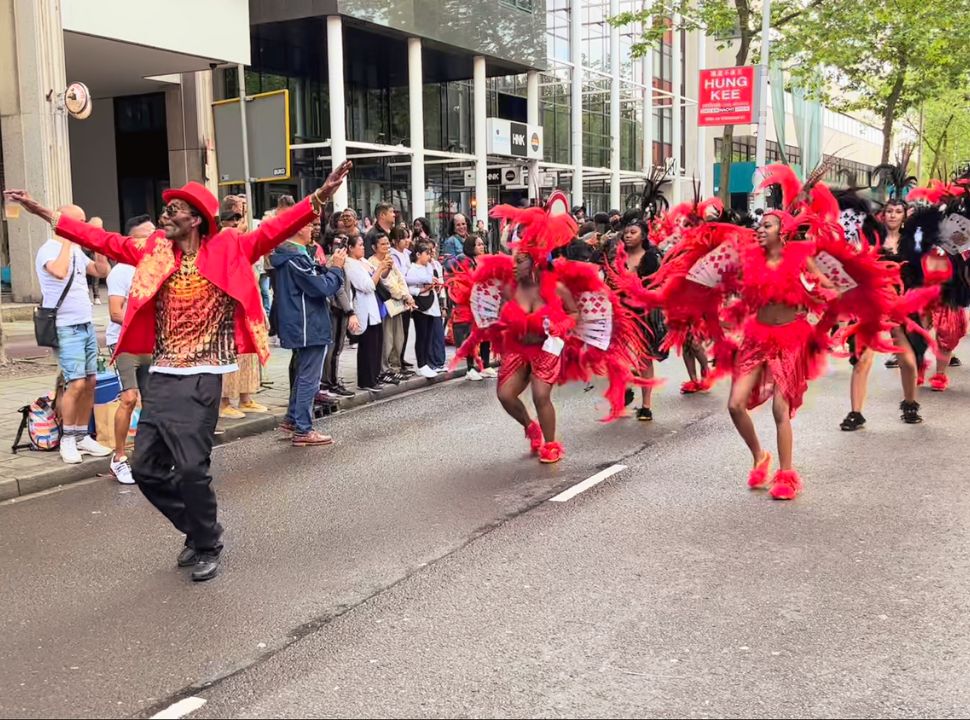 dancers dresses in red feathers passing the crows standing along the streets in Rotterdam