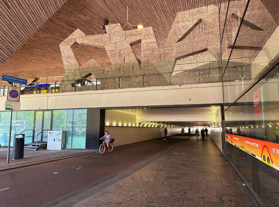 cyclists passing a tunnel that runs under the railway track of rotterdam station