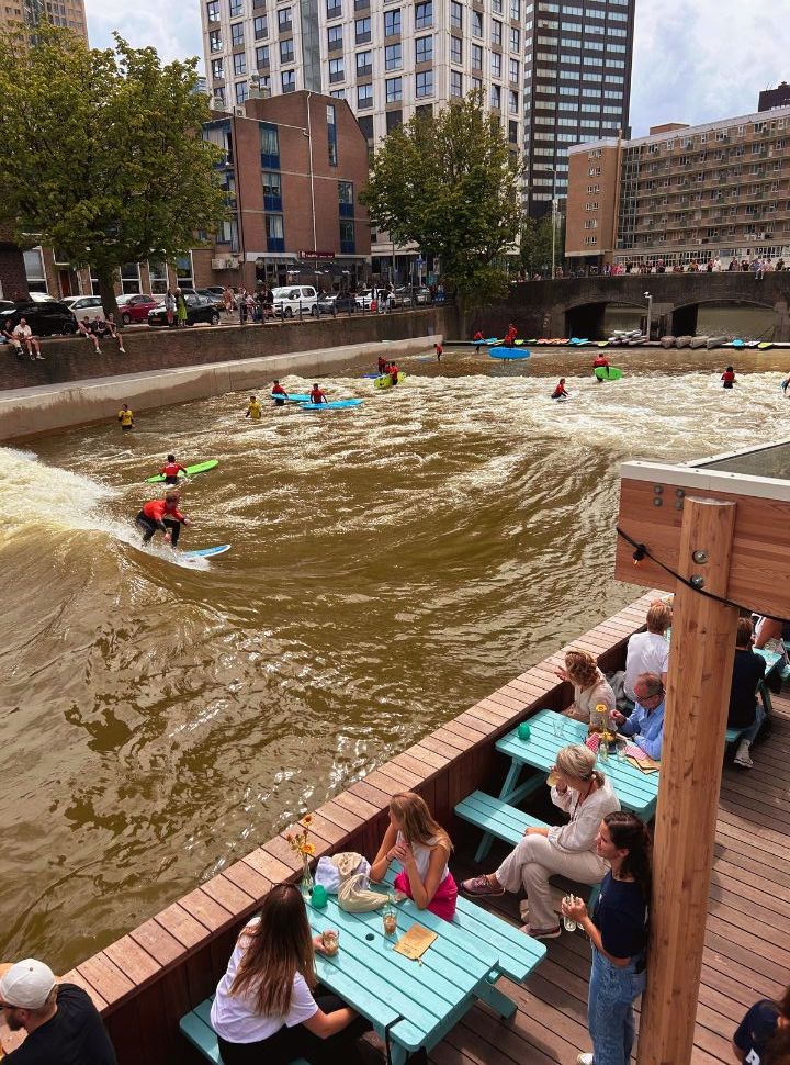 surfers surfing in a canal where artifical waves are created in the city of Rotterdam