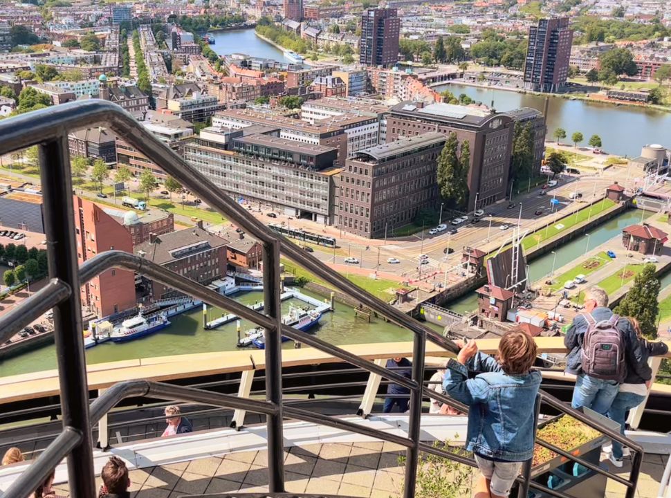 boy holding on to the stair railing at the observation deck with view of the old building in coolhaven rotterdam