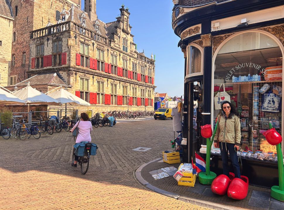 woman standing in front of a typical dutch souvenir shop located next to the historic delft city hall