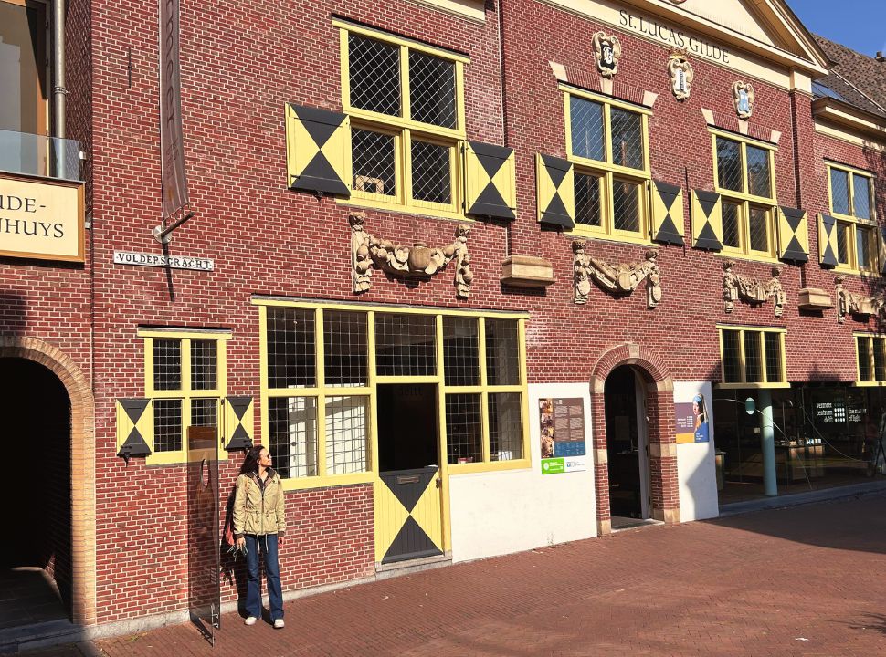 woman standing in front of a historic building where you can find the Vermeer musuem entrance