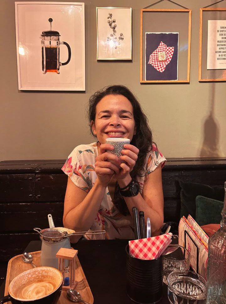 a woman smiling while drinking a warm drink