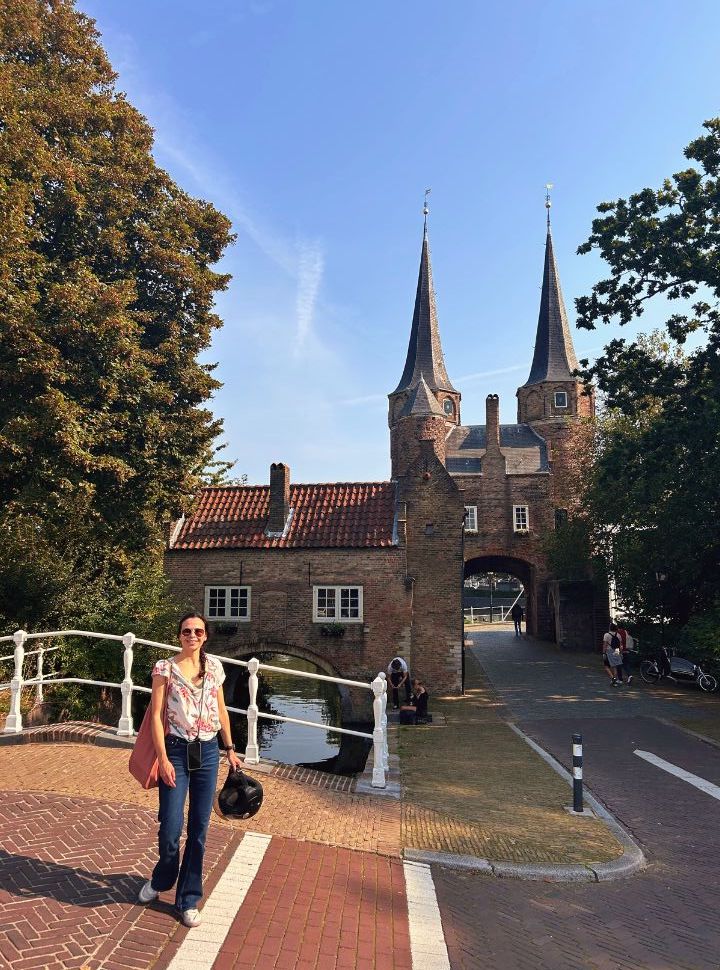 woman posing on a bridge with in the background the city gates with entrances through the canal or over the cycle path that runs through the gate with two towers