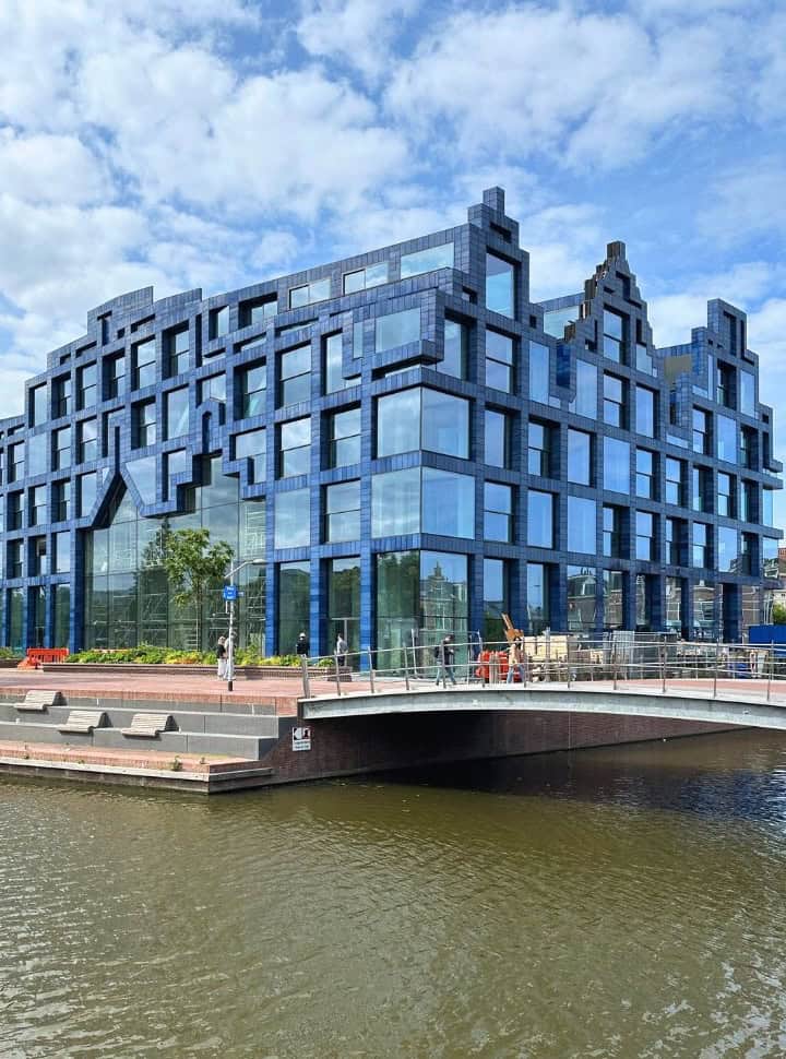 a modern building in along the canal of Delft which has features of a historic Dutch canal houses but the facade is from glass and modernized