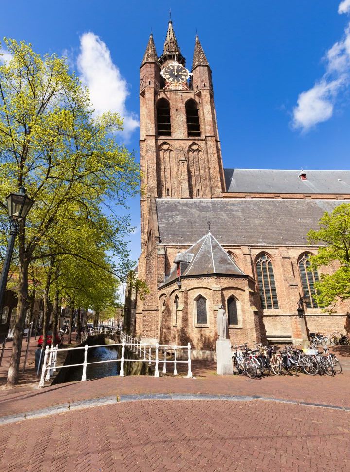 the old church of delft with its tower leaning slightly to the left, located right against the canal