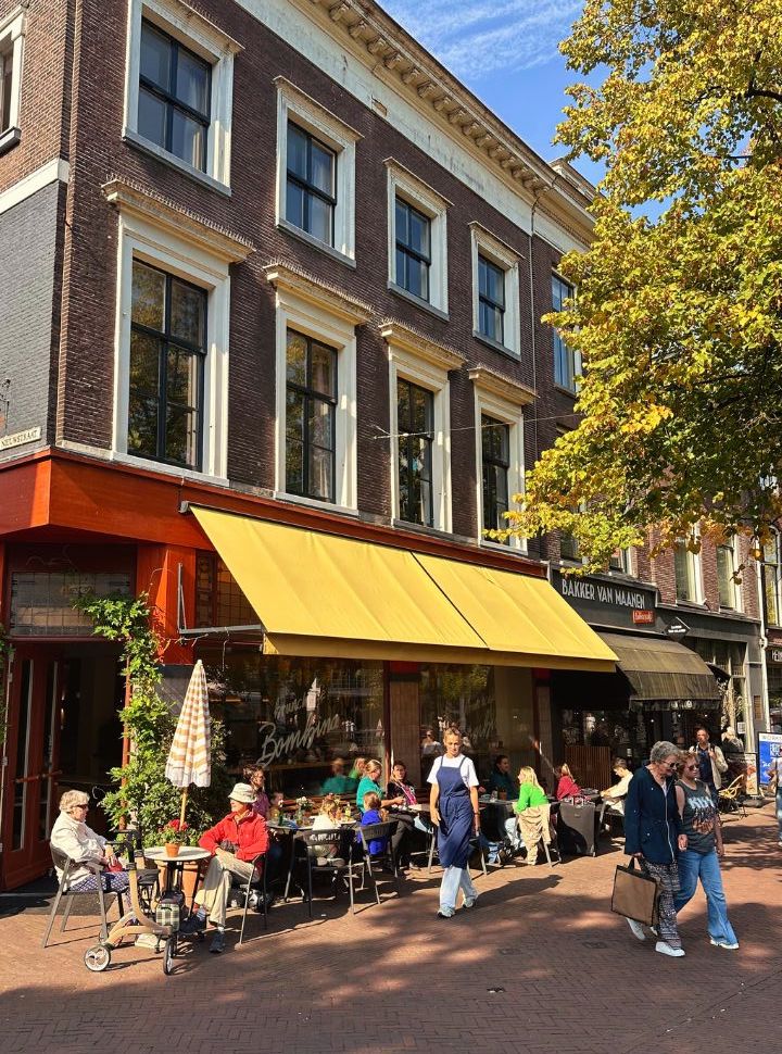 people enjoying lunch or coffee on a terrace outside a cafe in delft