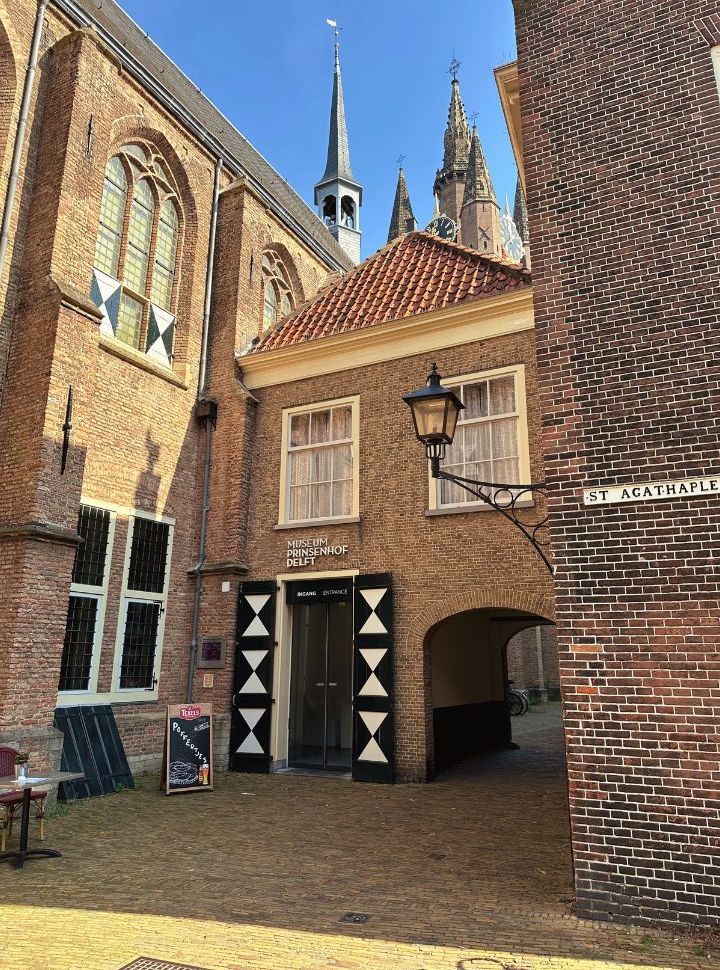 view of entrance to the prinsenhof museum with the tip of the old church tower in the back