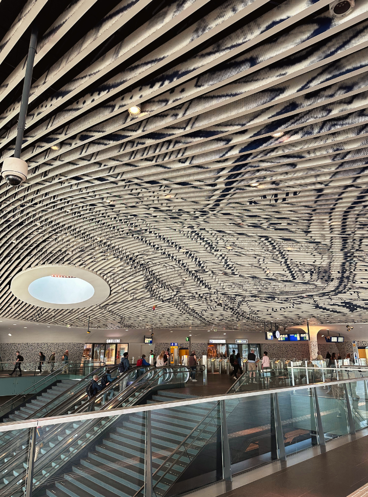 delft blue art incorporated in the ceiling of the train station in delft, escalators with passengers arriving