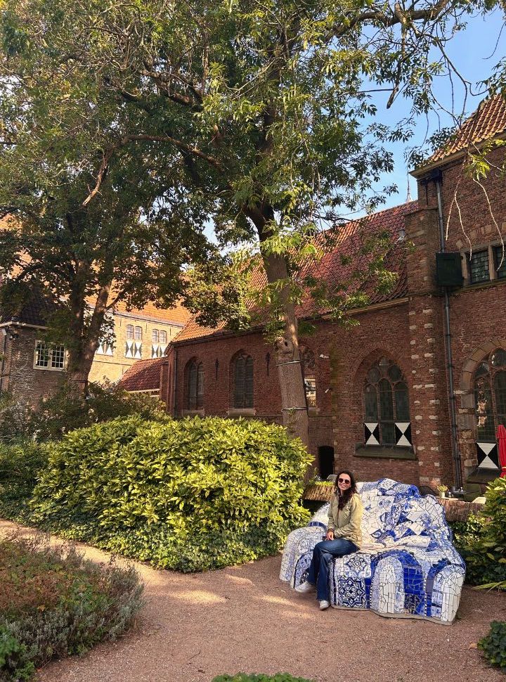 woman sitting on a seating area decorated with delft blue located in a garden of a former monastery in delft