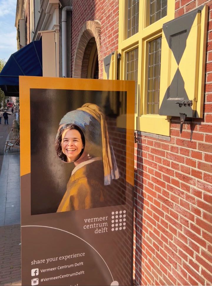 woman placing her head into a picture of the girl with the pearl earring painting found outside the vermeer centrum in delft