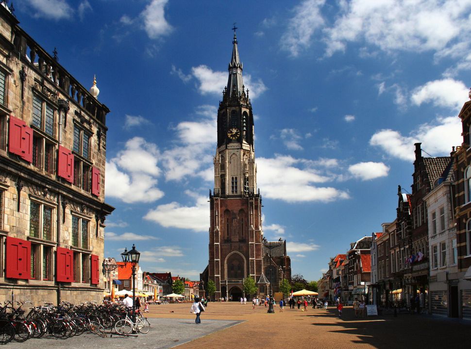 the gothic church in delft is located at the main square in town, and is surrounded by old buildings. the renaissance styled city hall is located accross it