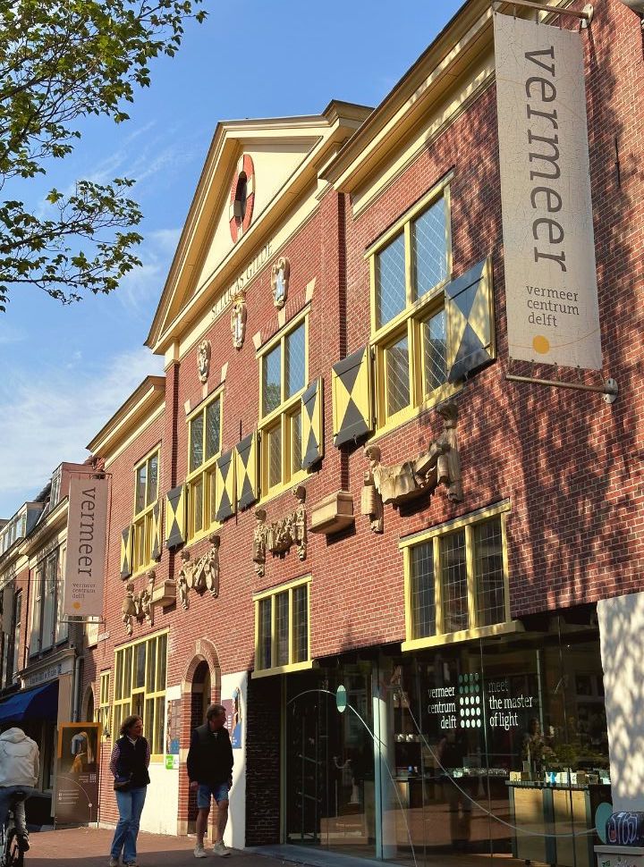 entrance to the vermeer centrum delft located within a beautiful historic building with yellow and grew shutters