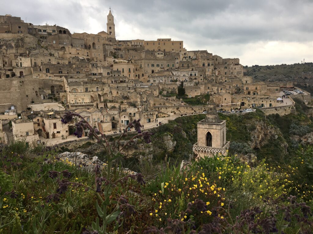 view of the old houses built on the hill slopes with a church tower perched on top in Matera Italy