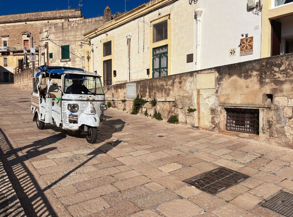 white tuk tuk going down hill in Matera town italy