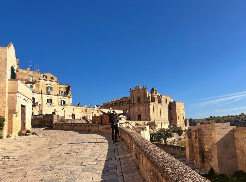 man standing along a road with ancient buildings in the back such as the Convent of Saint Agostino 