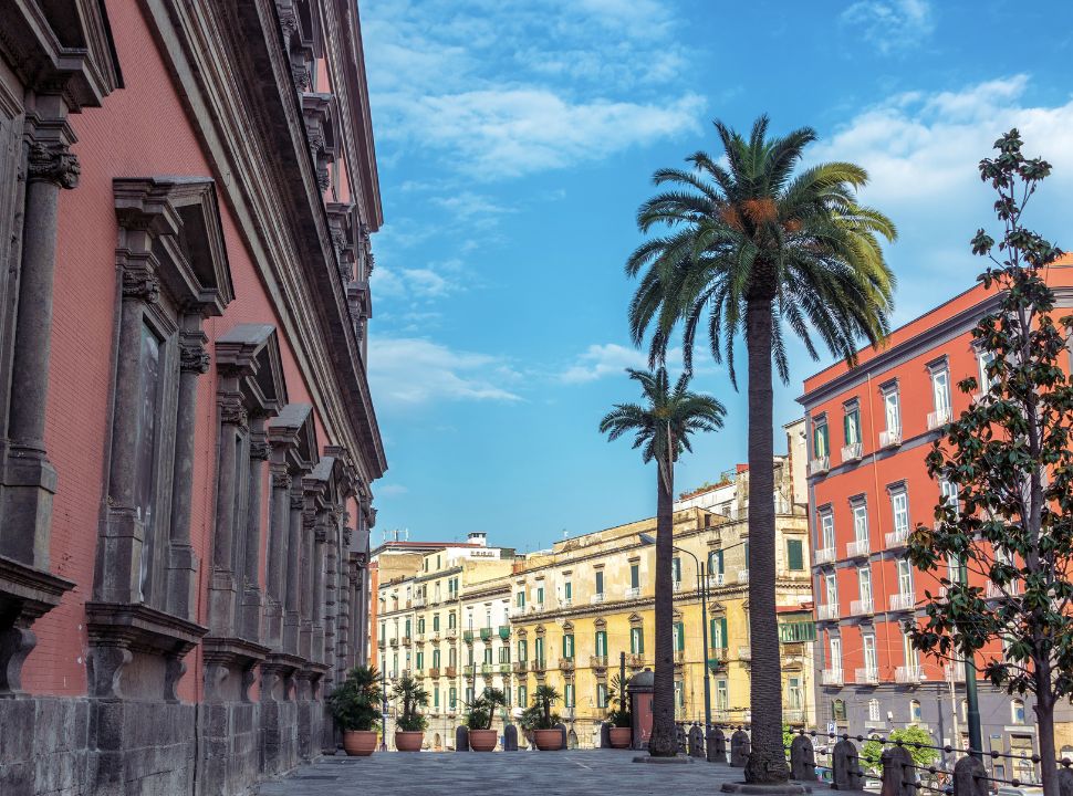 street in naples italy with tall colourful buildings and palm trees