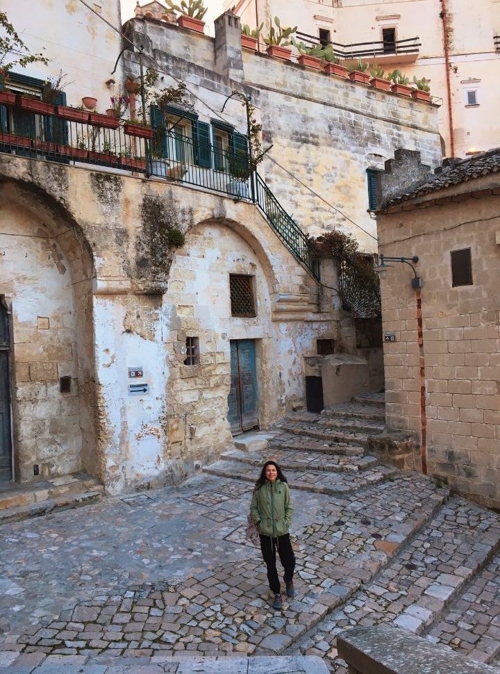 woman walking down the stairs between the old buildings of Matera Italy